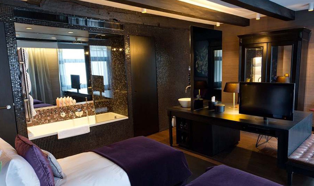 A luxurious hotel room in white, grey and black and a purple accent colour