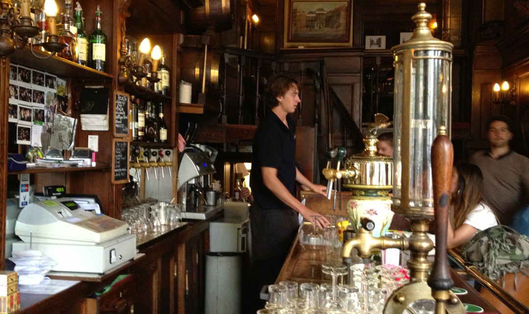 A view behind the bar to the barman. On the bar an original gin tap