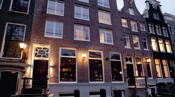 The façade of a stylish canal house lit up in twilight