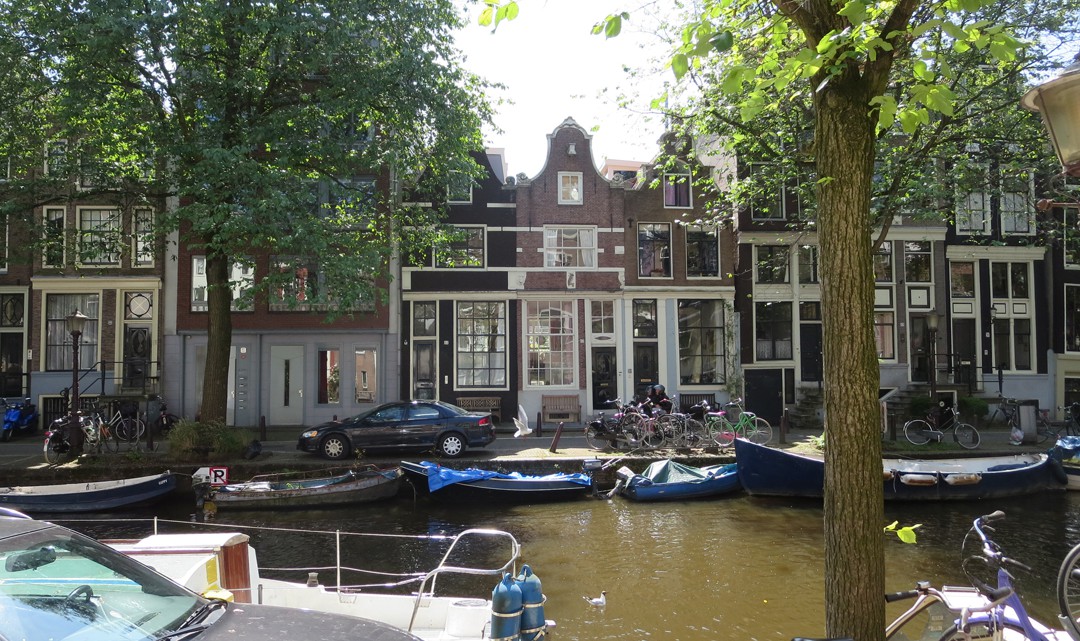 A row of canal houses and boats in the canals in front of them