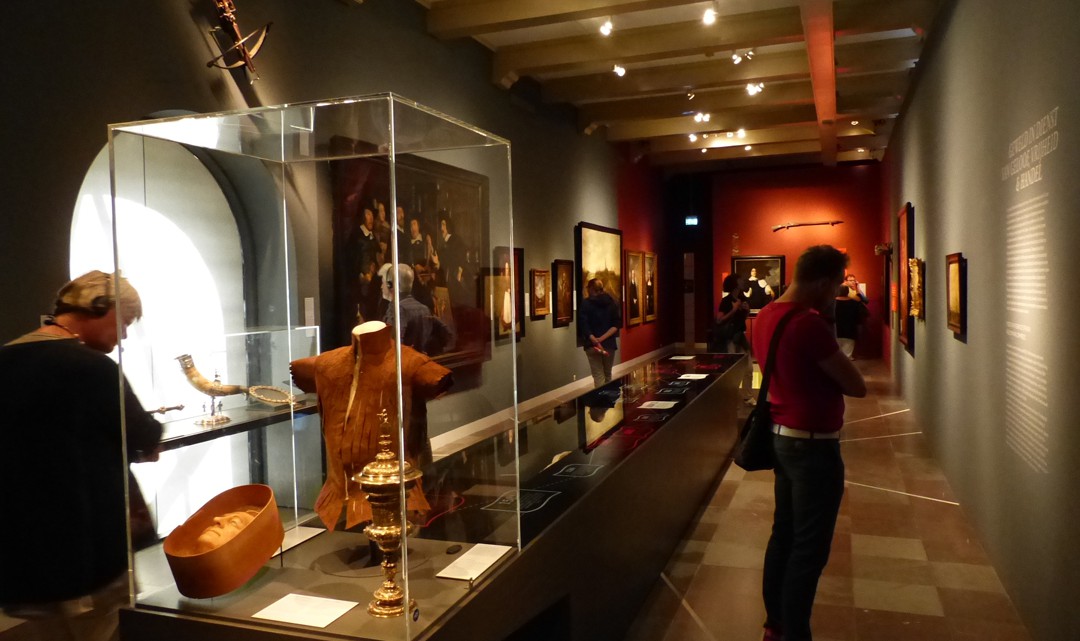 One of the exhibition rooms with paintings on the wall and various artefacts iin a display in the middle of the room