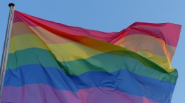 A rainbow flag against a blue sky