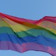 A rainbow flag against a blue sky