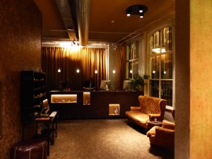 A dark photo of the reception desk with a light beige Chesterfield-like couch in front of it