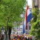 An enormous Dutch flag above a street full of people dressed in orange