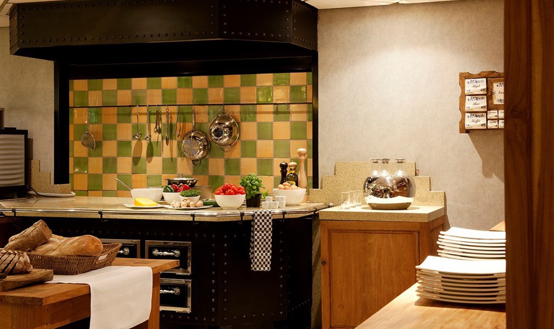 The kitchen with a copy of a historic looking stove, with white and green blocked tiles as splashback