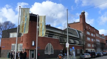 Peoppe standing in front of the entrance of the museum with promotional flags on the foreground