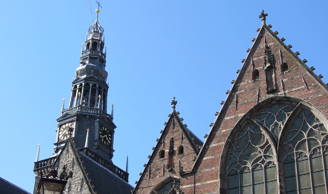 Top gables and spire of the old church against a blue sky