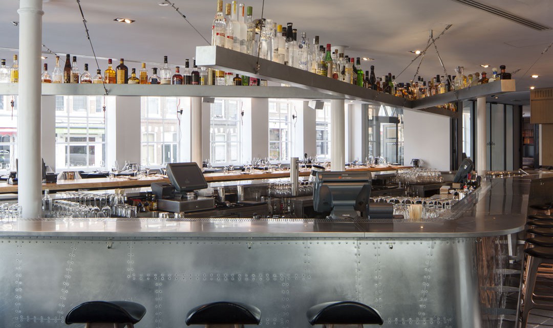 A closer look of the metal coated bar with bottles of liquor above the bar