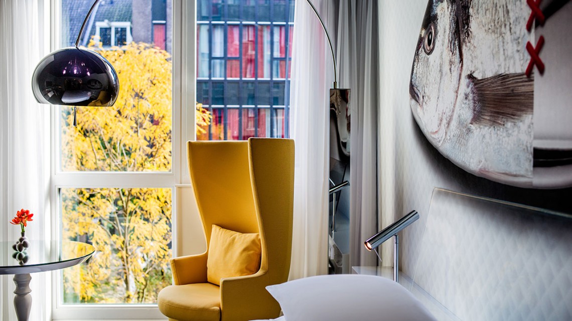 A yellow chair in front of the hotel room's window