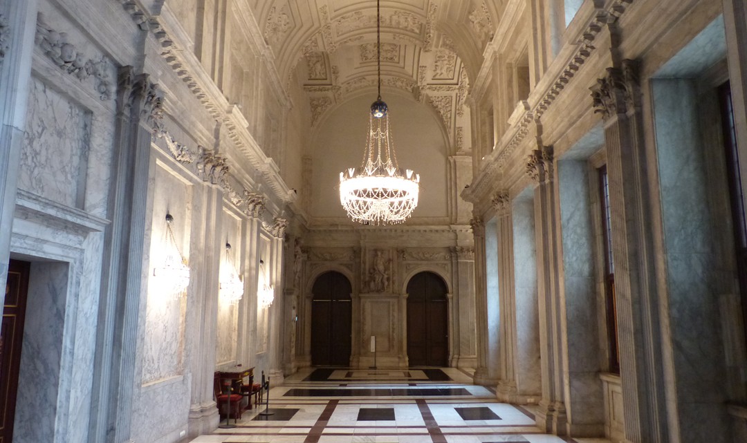 A light and high corridor with richly plastering on the ceiling and marble walls