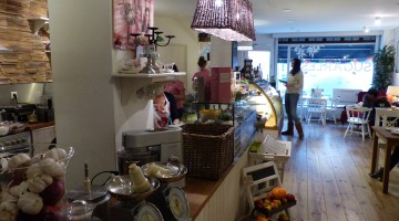 A view of the interior towards the front door. On and in front of the counter there are many organic vegetables and other ingredients displayed