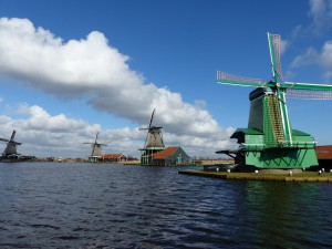 Four windmills in a row along the river in vivid colours against the blue sky