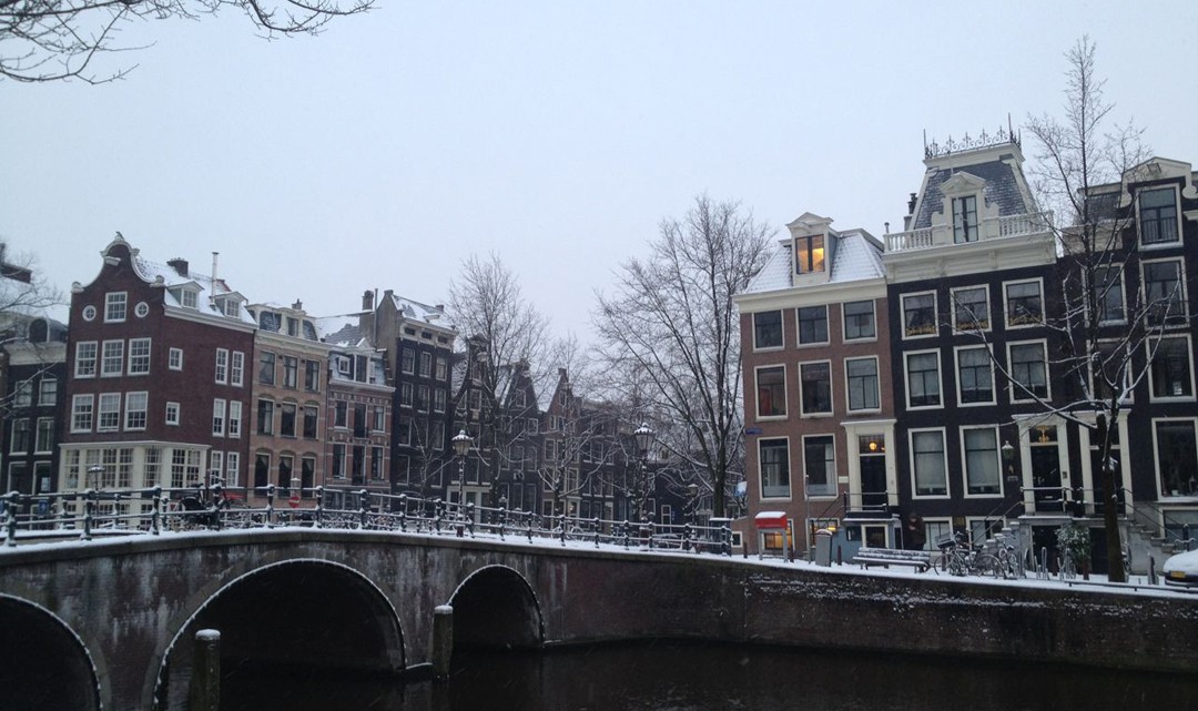 Snow on bridge and Amsterdam canal houses